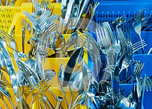 Silverware and cutlery in colorful palstic ocntainer in an industrial restaurant kitchen