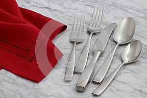 Silverware and hemstitch napkin on antique carrara marble