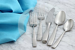 Silverware and hemstitch napkin on antique carrara marble