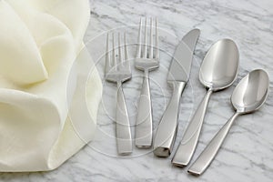 Silverware and hemstitch napkin on antique carrara marble