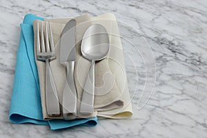 Silverware and hemstitch napkin on antique carrara marble