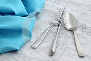 Silverware and hemstitch napkin on antique carrara marble