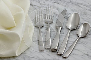 Silverware and hemstitch napkin on antique carrara marble