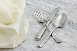 Silverware and hemstitch napkin on antique carrara marble