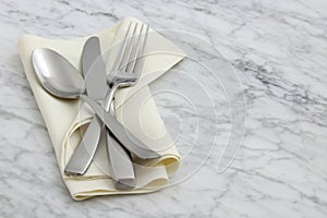 Silverware and hemstitch napkin on antique carrara marble