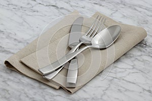 Silverware and hemstitch napkin on antique carrara marble