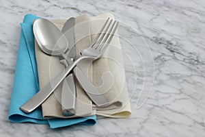 Silverware and hemstitch napkin on antique carrara marble