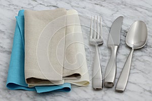 Silverware and hemstitch napkin on antique carrara marble