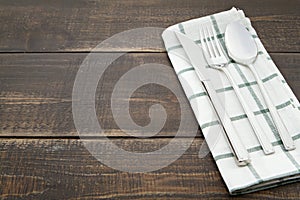 Silverware and napery on wooden background.