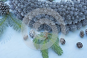 Silvery Christmas wreath of small cones and branches of a Christmas tree on a light background.