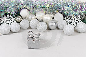 Silvery gift boxes on a blurred background with white and silver balls, garland and tinsel. Christmas card with white