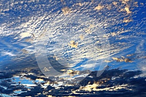 Silvery shimmering clouds in blue sky by sunset light