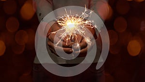 Silvester Party / New Year background banner - Young happy pretty woman with gray pullover holding a sparkling sparkler in her