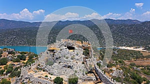 Simena castle in Kalekoy and Turkish flag waving in hot summer breeze