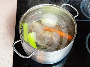 Simmering beef broth in stockpot on ceramic cooker photo