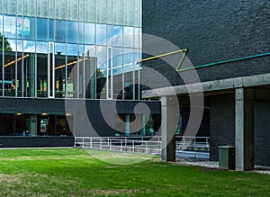 Simmetry in Modern Architecture. Reflection of clouds in glass windows and green lawn in front. Technical University of