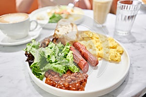 Simple American style Breakfast with sausages, scrambled eggs, baked beans, mushrooms and tomatoes. This dish is full of