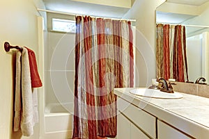 Simple bathroom with red and brown colors in shower curtain and