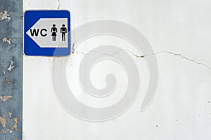 A simple blue and white sign indicating the location of public restrooms in a city.