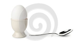 Simple breakfast scene featuring a boiled egg in an egg cup with a spoon