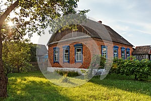 simple brick village house with a lawn in the yard at sunset sunrise in the tranquility of the countryside