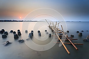 A simple bridge made of bamboo adorns the coast of Jakarta during a very beautiful and enchanting sunset