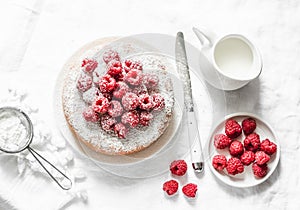 Simple cake with powdered sugar and fresh raspberries on a light background. Summer berry dessert.