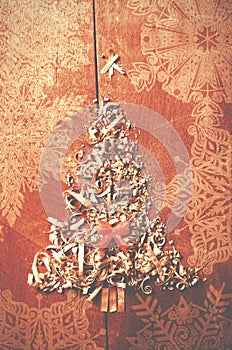 Simple Christmas tree arranged from sawdust, wood-chips on wooden background. Orange cute ribbon.