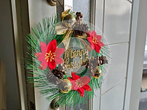 Simple Christmas wreath is hanging on the front door handle