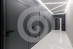 Simple clean newly built generic modern new real estate block of flats interior, long black corridor with black doors, perspective