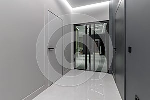 Simple clean newly built generic modern new real estate block of flats interior, long black corridor with black doors, perspective