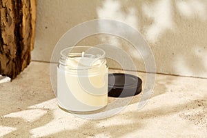 Simple composition with aromatic burning candle in jar. Mockup soy wax candle with wick in natural style. Scented handmade candle