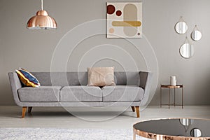 Simple couch with pillows in a living room decorated with copper lamp, mirror and painting