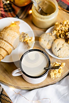 Simple country home breakfast in bed, coffee with milk and homemade pastry on plaid blanket