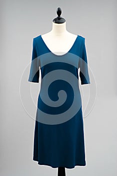 Simple, dark blue dress displayed on a white, headless mannequin