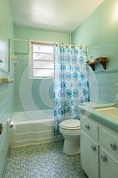 Simple dated 1950s bathroom with green tile. photo