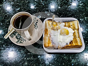 Simple English breakfast with fried eggs, toast and tea on black background