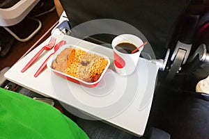 Simple in-flight meal of rice, meat, coffee in disposable utensils