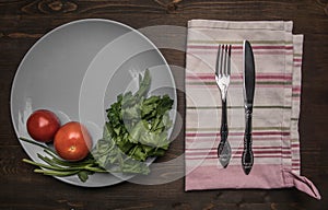 Simple food, tomatoes, parsley and penne pasta on a gray plate, lined on a wooden background, top vie