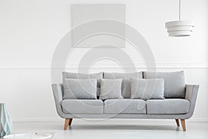 Simple grey couch in bright scandinavian living room interior