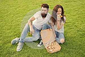 Simple happiness. Cheat meal. Couple eating pizza relaxing on green lawn. Fast food delivery. Bearded man and girlfriend