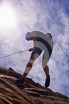 The simple joys of rock climbing. a young female rock climber abseiling down a mountain.