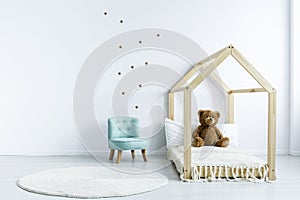 Simple kid room interior with diy bed with a teddy bear, armchair, round rug and stars on the wall. Place for your product