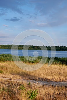 Simple landscape structured in horizontal patterns of different colors containing a blue sky with a river in the middle