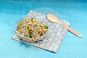 Simple lentil salad with pickles, parsley, and pasta on turquoise table on napkin and red spoon