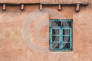 Simple little house with smooth brown walls and blue windows  in Santa Fe, New Mexico