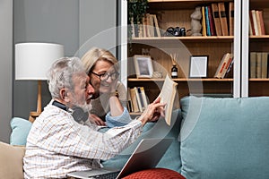 Simple living. Elderly retired couple enjoying their retirement, reminiscing entertaining in their warm home. Senior people