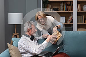 Simple living. Elderly retired couple enjoying their retirement, reminiscing entertaining in their warm home. Senior people