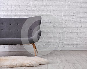 Simple living room interior with comfortable sofa near brick wall.