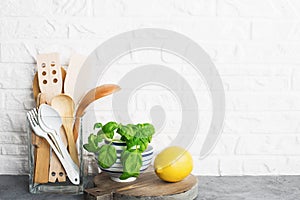 Simple minimalist kitchen shelf. Cutlery, kitchen tools, greens in a glass, fruits on a light background. Scandy style